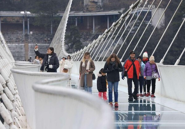 Foreign tourists walk on a glass-bottomed bridge at Zhangjiajie Grand Canyon, central China's Hunan province. (Photo by Wu Yongbing/People's Daily Online)