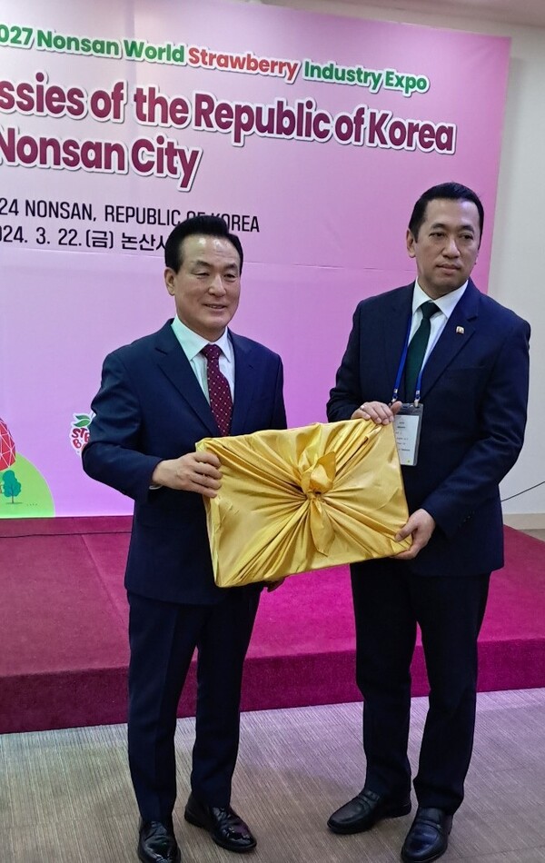 Mayor Baek of the Nonsan City (left) presents a large box of juicy strawberries of Nonsan to Ambassador U Thant Sin of the Union of Myanmar who received it in his capacity as Dean of the visiting Members of the Seoul Diplomatic Corp that day. This box of straw berries was later presented to each member of the 50 embassies in Seoul attending the Strawberry Festival in Nonsan.
