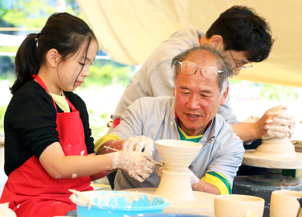 A ceramics expert helping a child make a shape out of clay