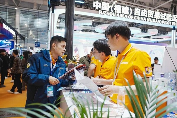 Staff members of an exhibitor at the 4th China Cross-border E-commerce Trade Fair in Fuzhou, southeast China's Fujian province talk to a visitor, March 18, 2024. (Photo by Xie Guiming/People's Daily Online)
