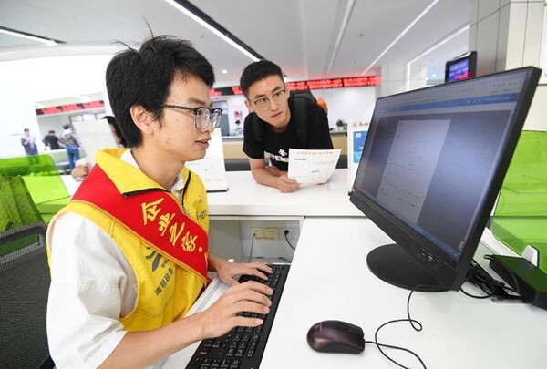 A staff member of a government service center in Nanming district, Guiyang, southwest China's Guizhou province, records demands of an enterprise. (Photo by Zhao Song/People's Daily Online)