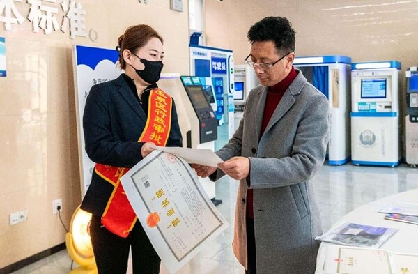 A self-employed individual receives business licenses at a government service center in Yuquan district, Hohhot, north China's Inner Mongolia autonomous region, March 7. 2024. (Photo by Ding Genhou/People's Daily Online)