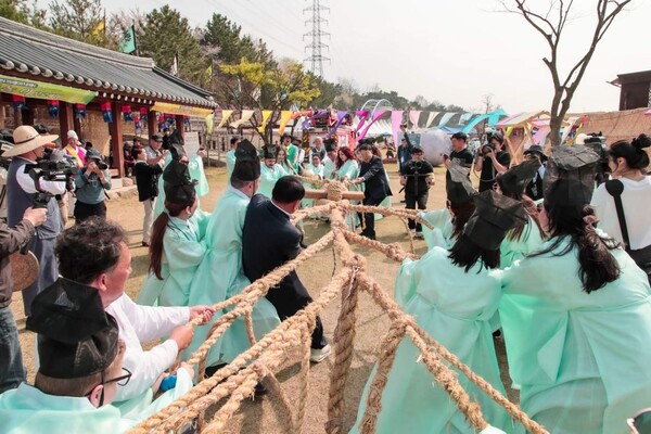 Team members, divided into two groups, pulling the rope in unison and in force for winning