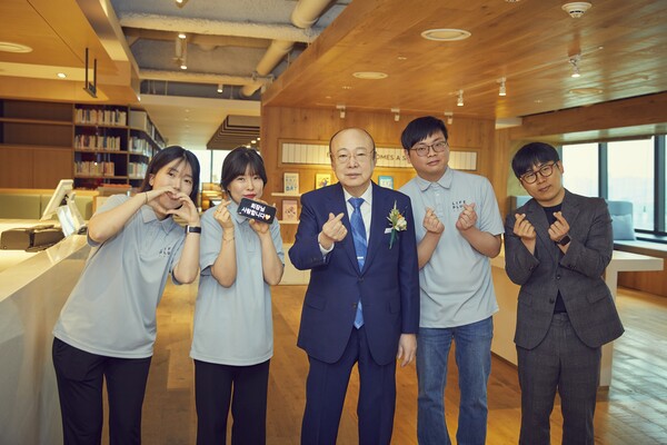 Here's the translation: "Chairman Kim Seung-yeon of Hanwha Group is taking a commemorative photo with a hearing-impaired barista employee at an in-house café."